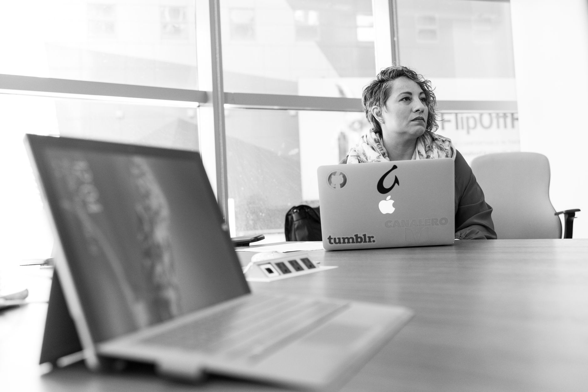 Businesswoman using laptop in a bright office setting, focused on her tasks.