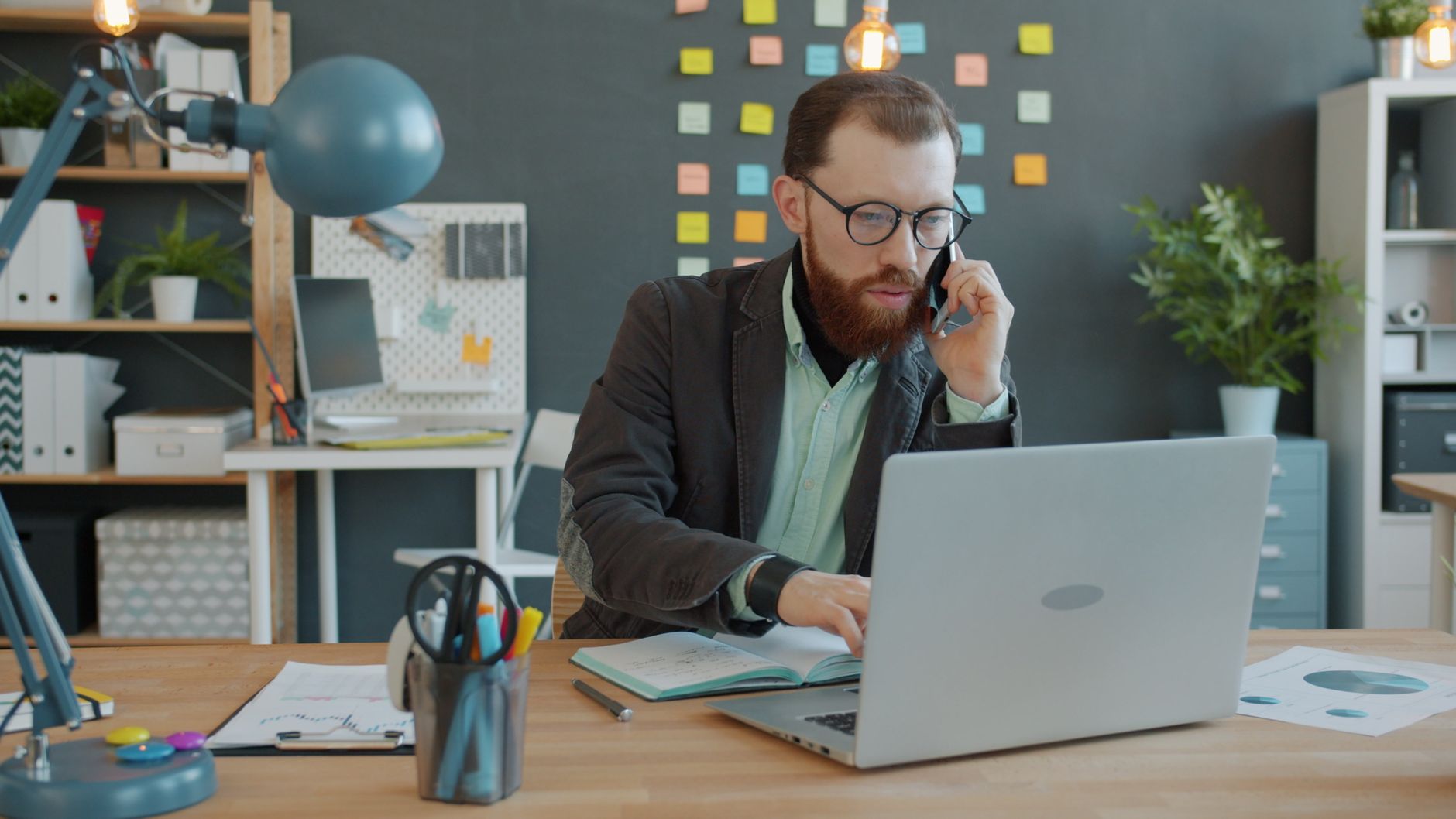 Professional businessman on a call while working on a laptop in a trendy office.
