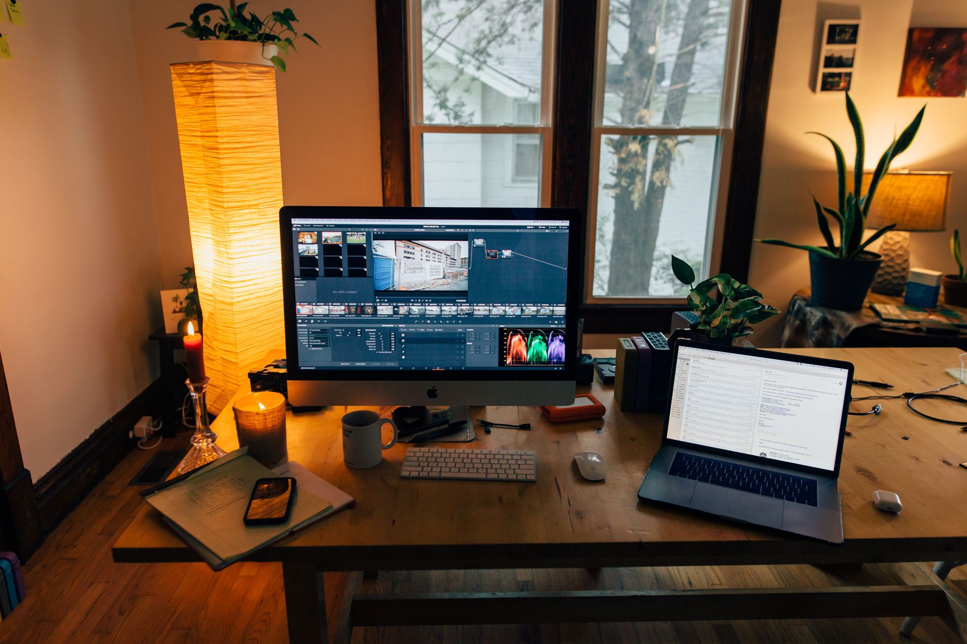 From above of laptop with computer monitor and keypad with smartphone in room with candle and lamp light